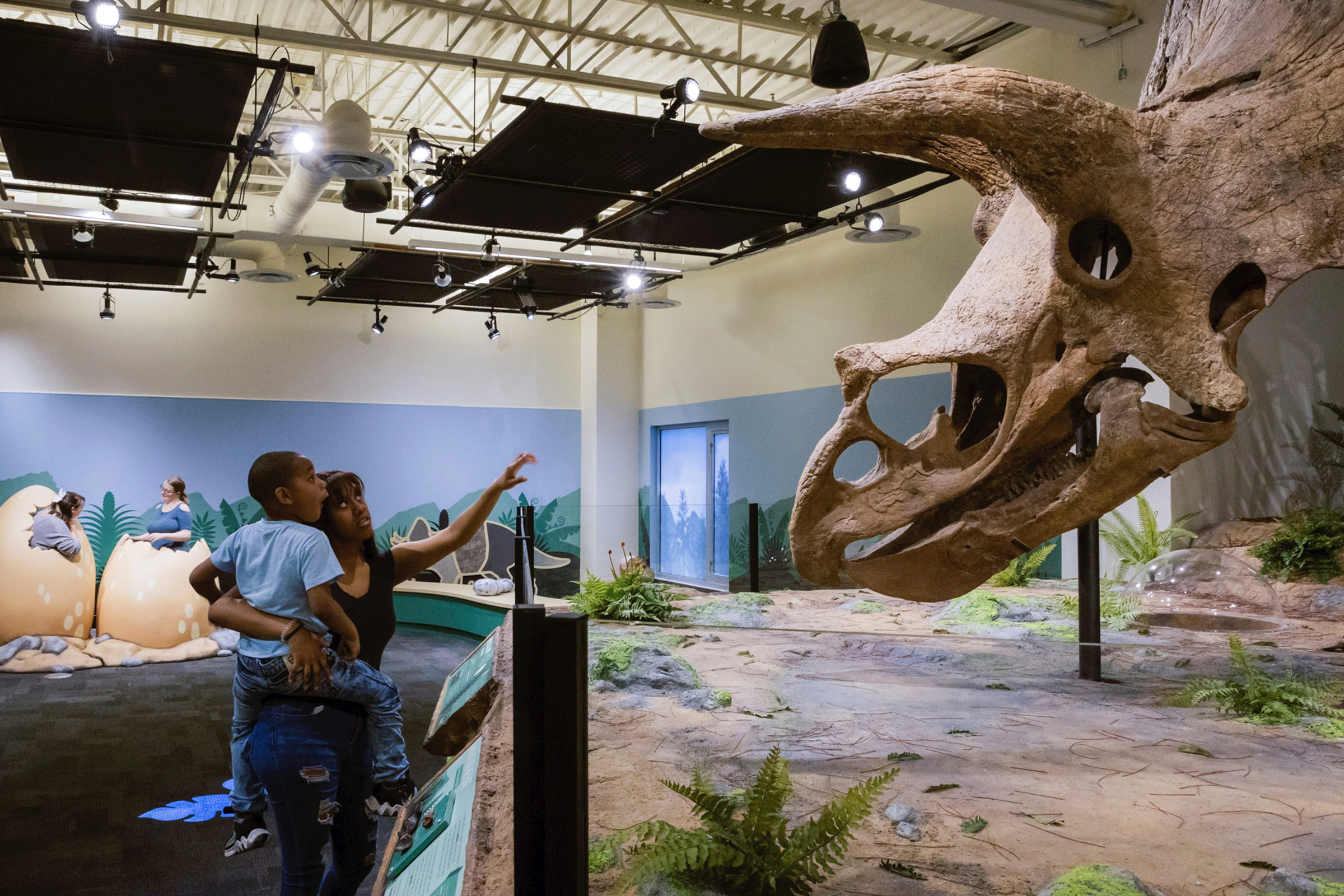 Parent holding child and showing them the dinosaur fossil