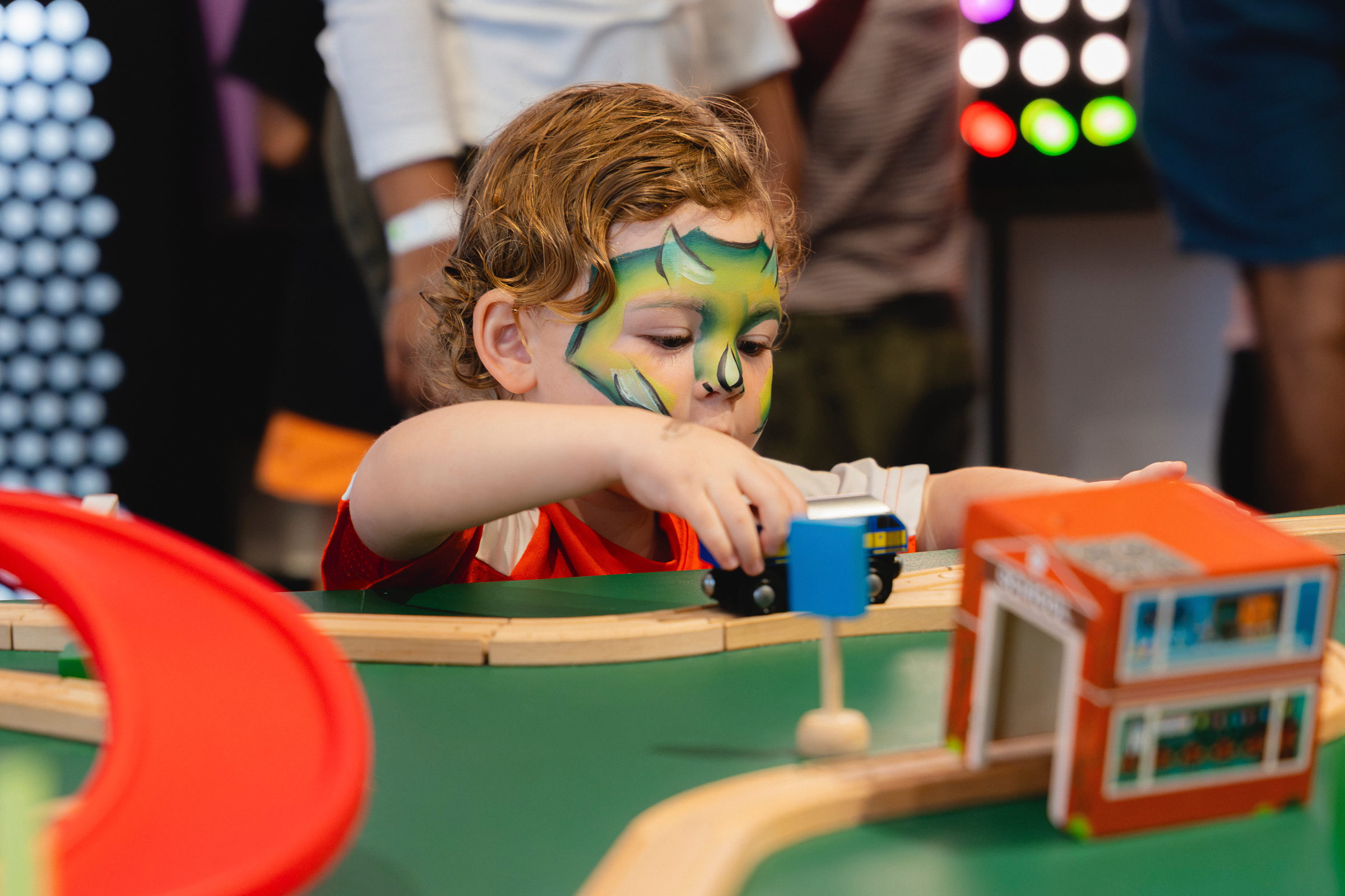 Child with face paint playing with toy blocks