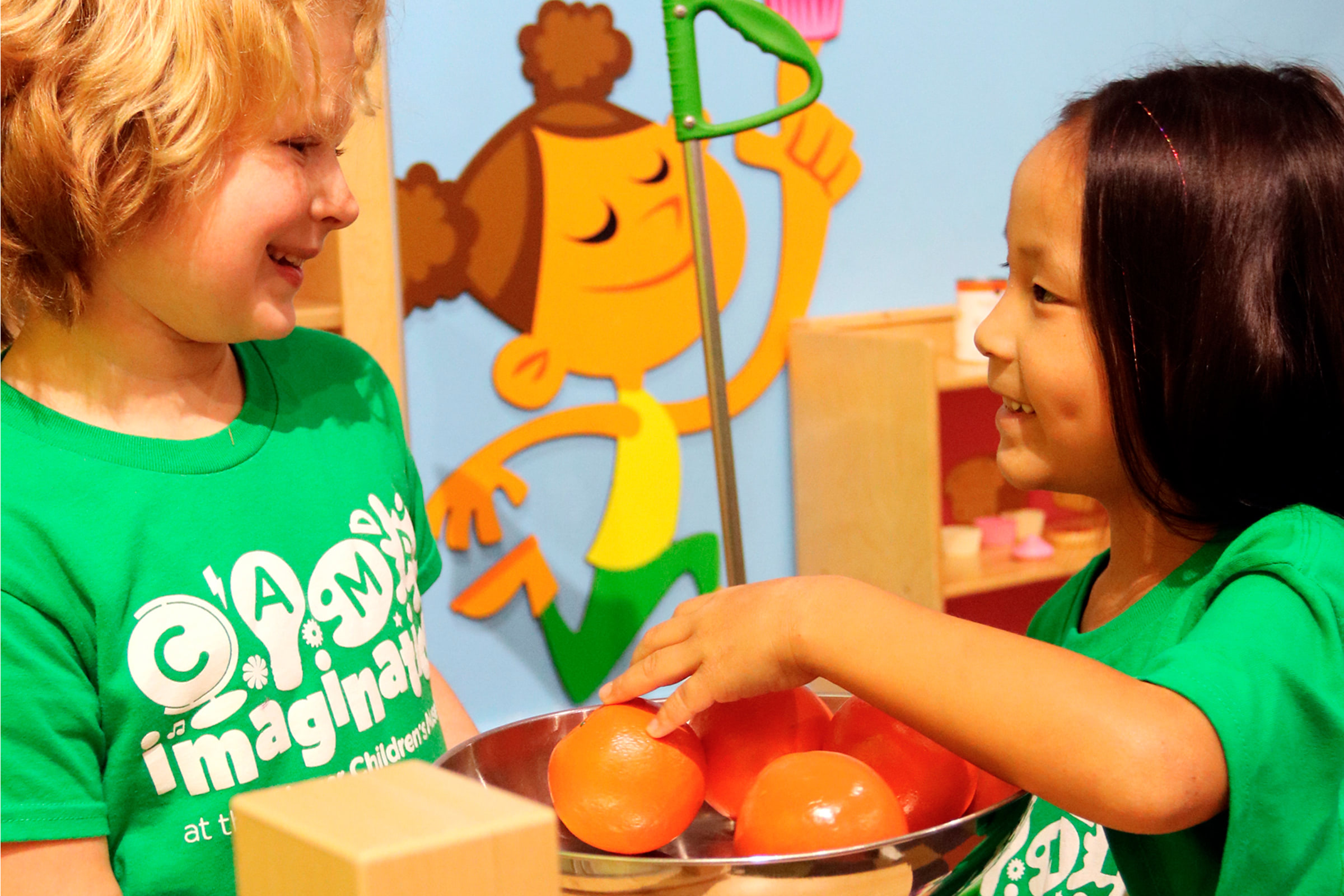 two kids smiling at each other and playing with play fruit