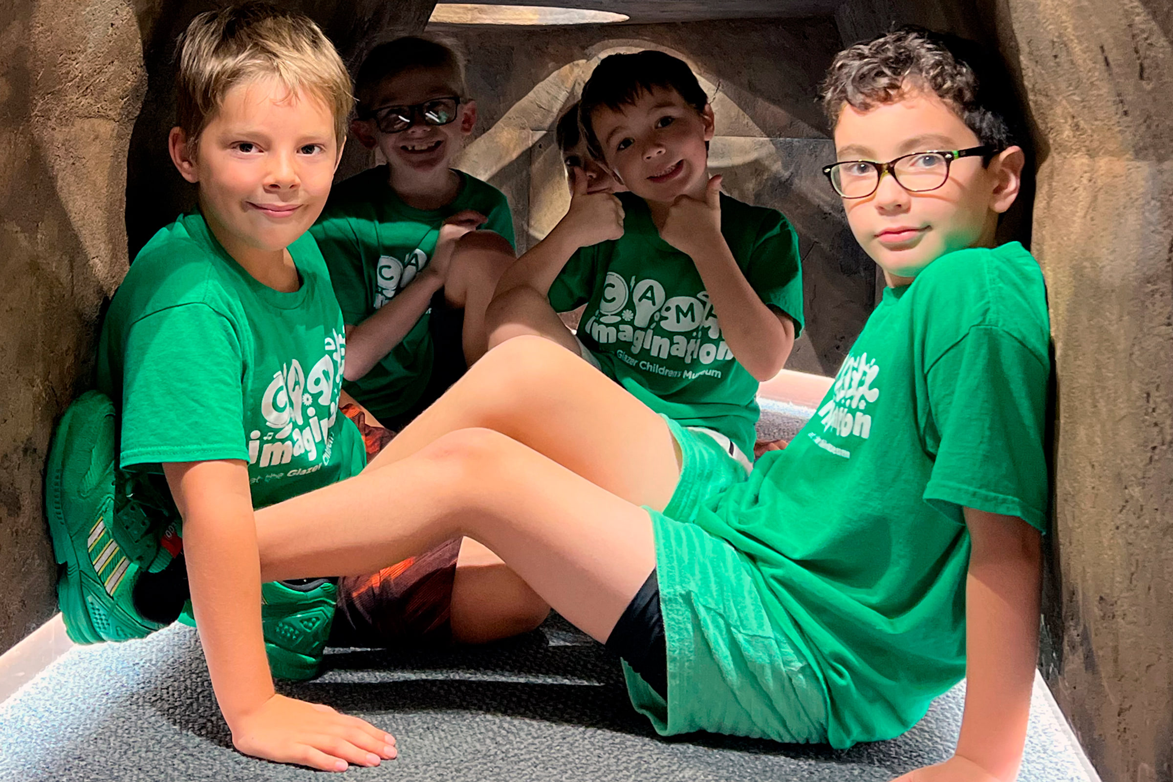kids in green shirts playing in a cave exhibit