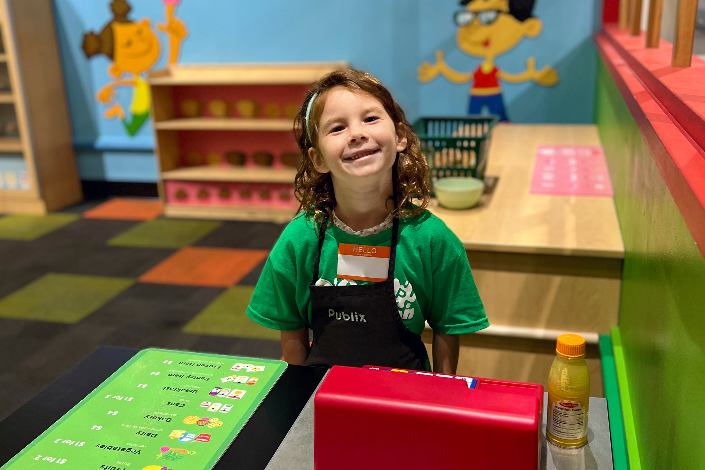 kid in a Publix apron playing at a toy cash register