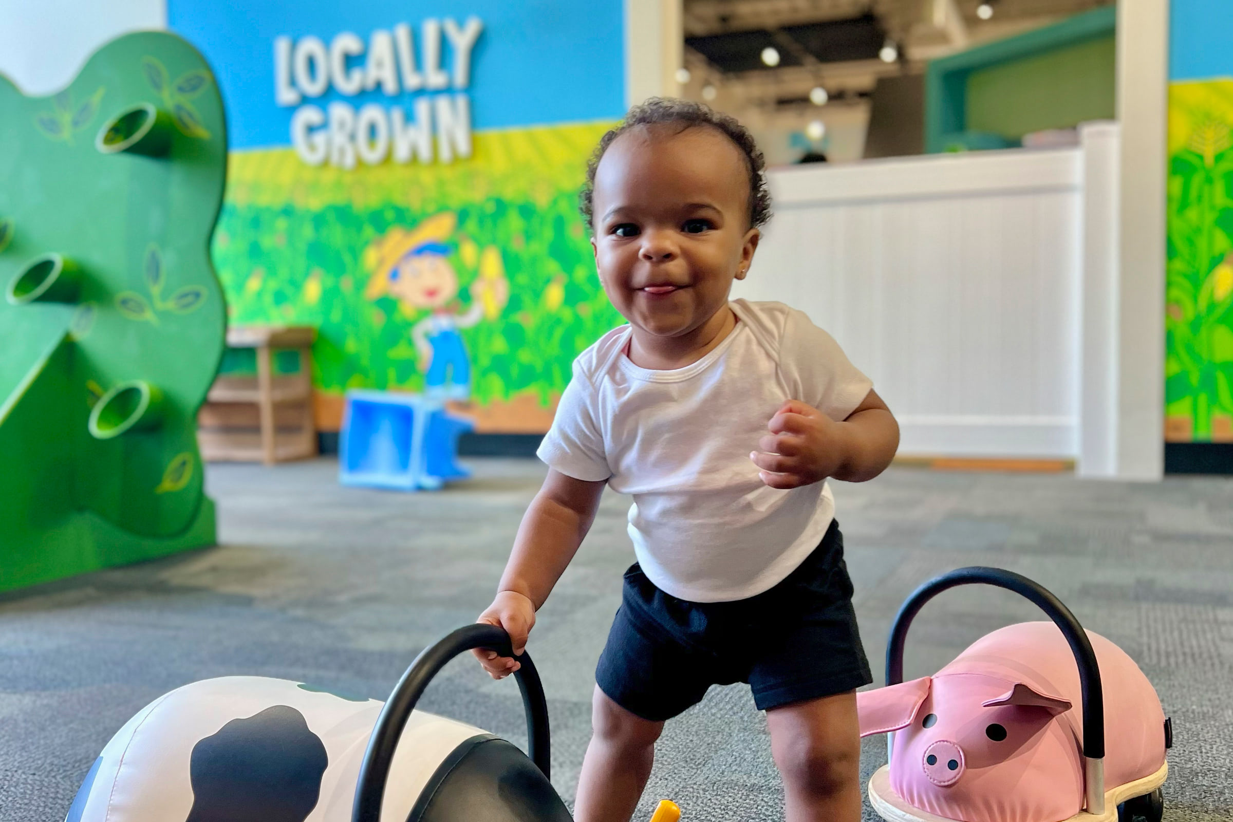 Toddler playing with a cow stuffed animal and smiling