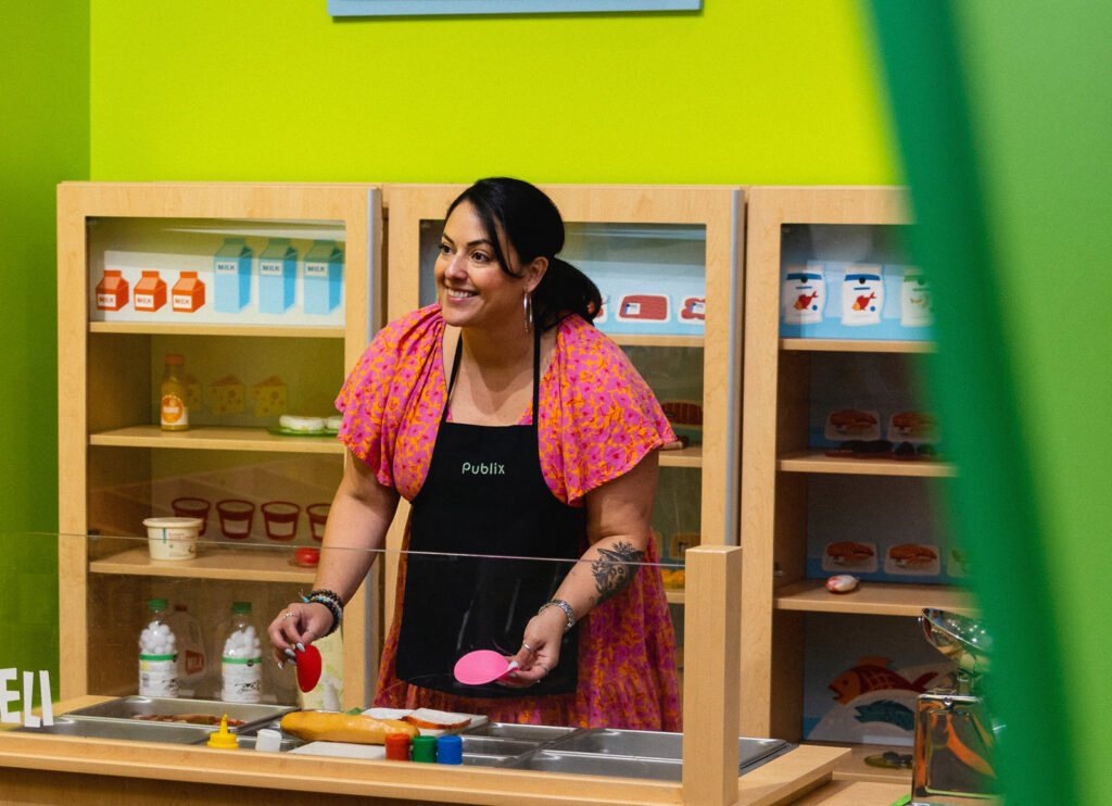 Woman wearing Publix apron making a pretend sandwich
