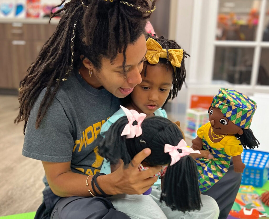 parent playing with dolls with their child