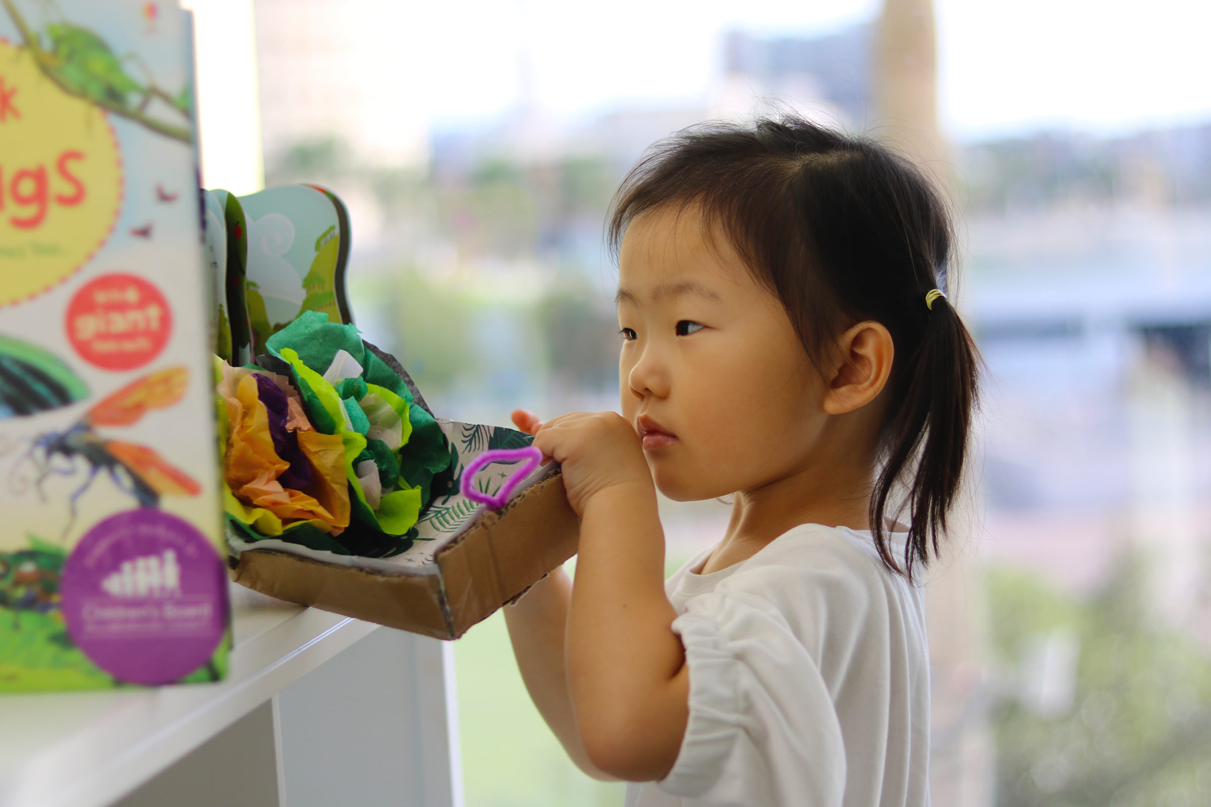 toddler with pigtails, playing with toys at Glazer Children's Museum