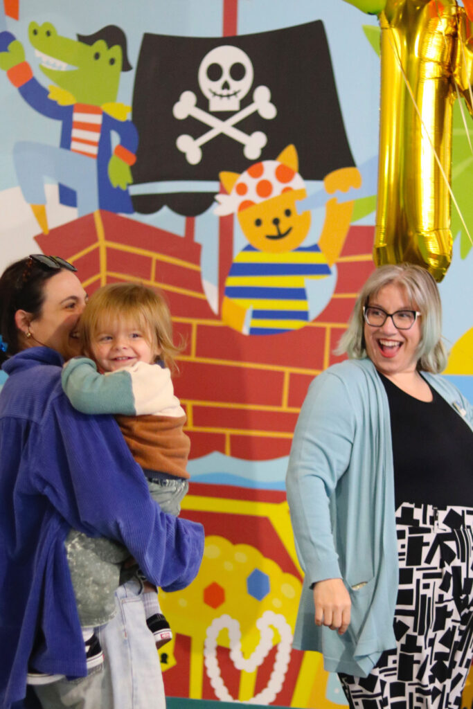 Two adults smiling with toddler