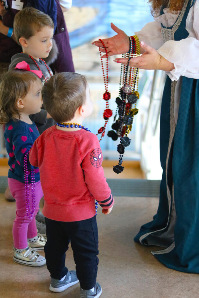 An adult handing beaded necklaces to children