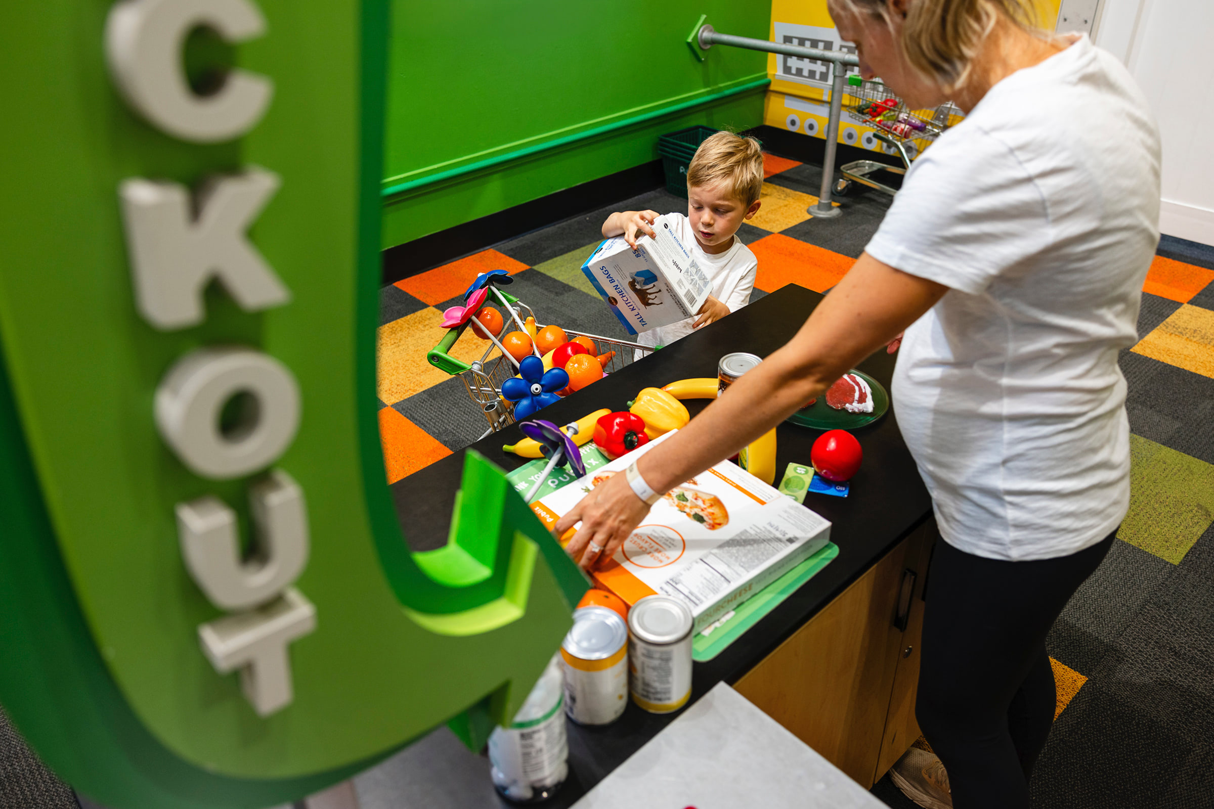 parent and child playing at grocery store play station