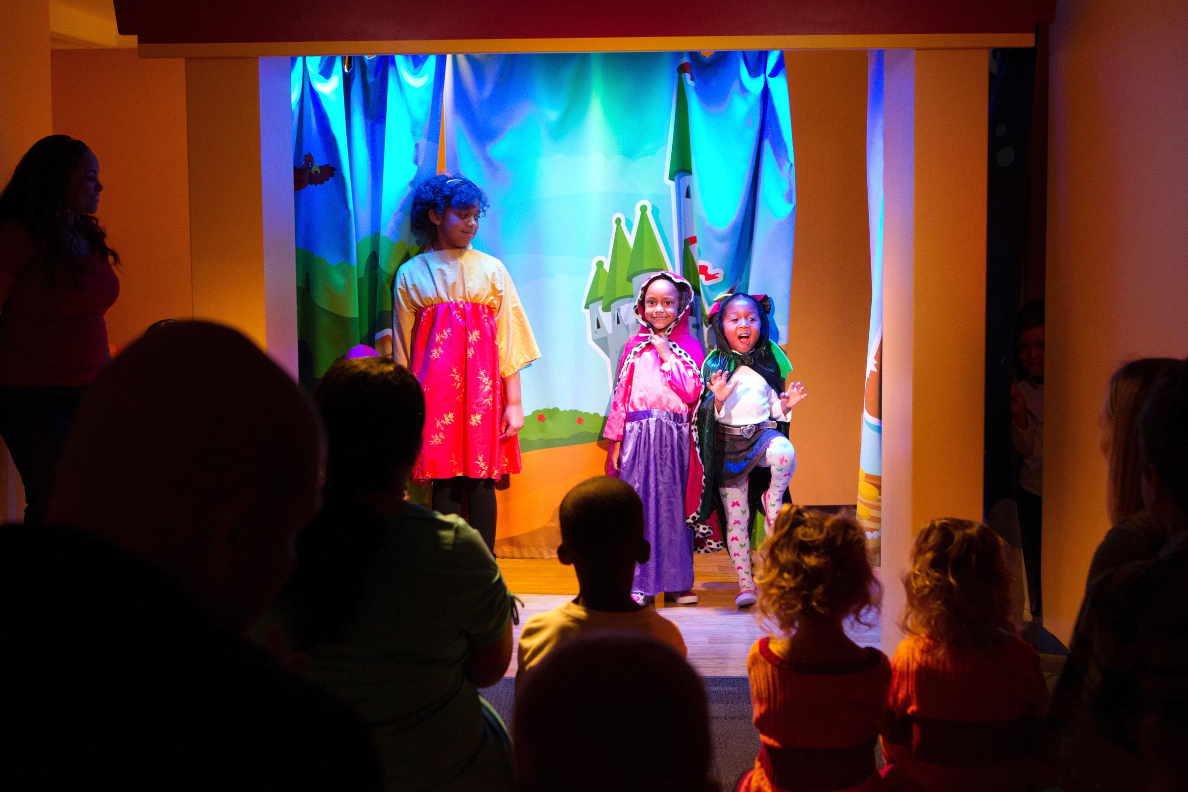 Three children on a stage performing a play for parents and their children