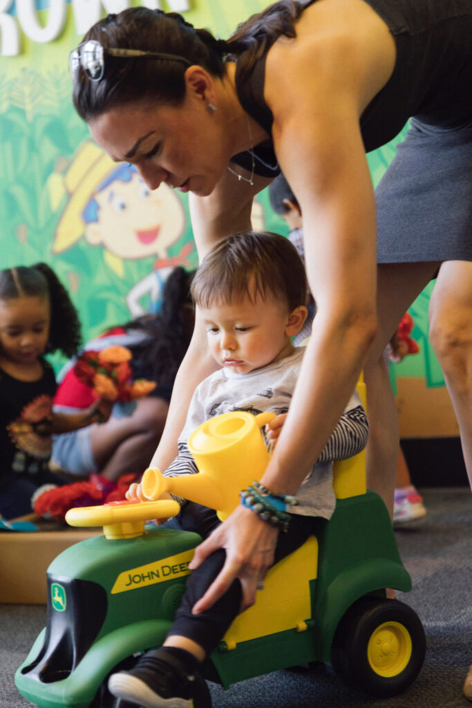 Parent pushing toddler on a toy tractor